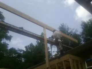 Carpenter setting a ridge beam over a new addition frame — Ice Dam Removal by Roofing Brothers in Clancy