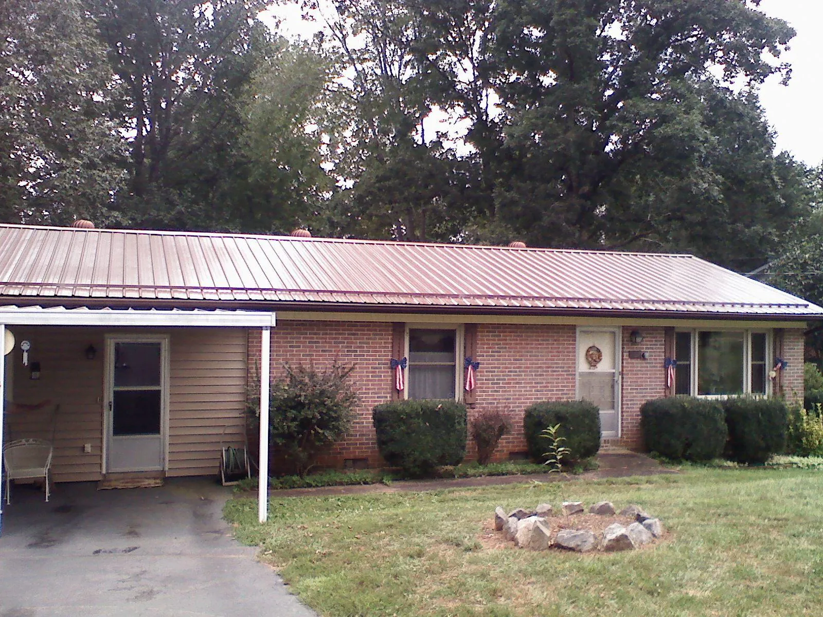 Bronze metal roof and carport on a brick ranch home — Roof Repair work by our crew in Clancy
