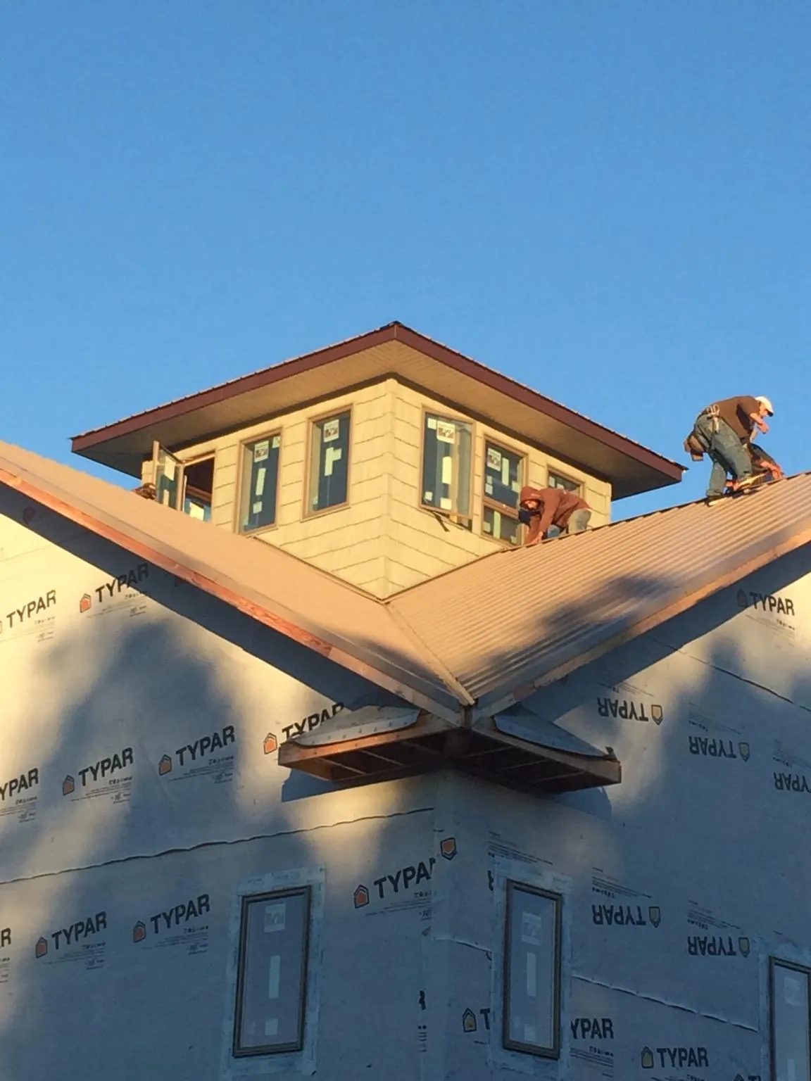 Roofers working around a rooftop cupola on a new metal roof at sunset — Roof Waterproofing in Clancy by Roofing Brothers